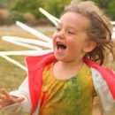 Autonomia infantil: Foto de uma criança correndo e se divertindo em campo aberto. Ela veste uma blusa suja de tinta