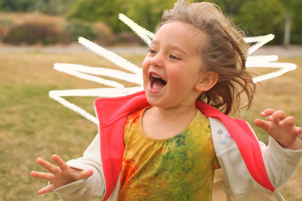 Autonomia infantil: Foto de uma criança correndo e se divertindo em campo aberto. Ela veste uma blusa suja de tinta