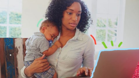 Mãe negra vestindo uma camisa branca está com um bebê no colo e ao mesmo tempo trabalhando com um notebook