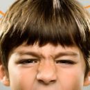 Foto de um menino com os olhos contraídos mostrando irritação