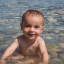 Foto de um bebê sorrindo sentado na água