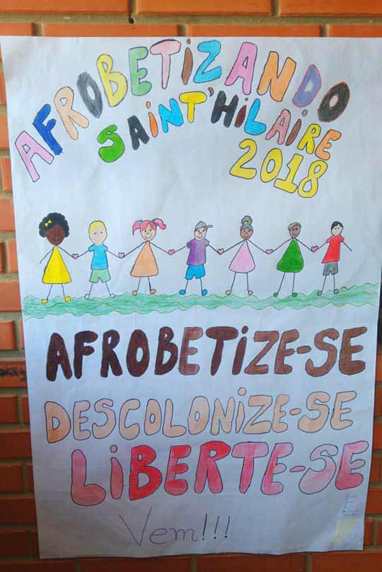 Foto de um cartaz colado na parede da escola, dizendo afrobetize-se, descolonize-se, liberte-se