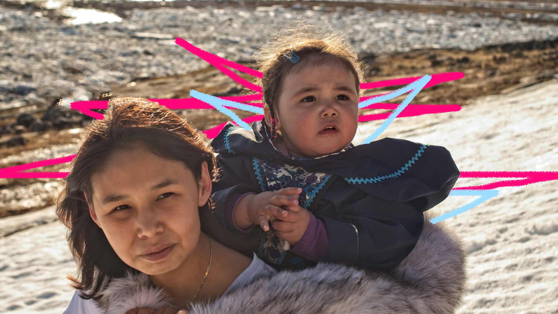 Foto de mãe e filha indígenas olhando atentamente. A criança está nas costas de sua mãe