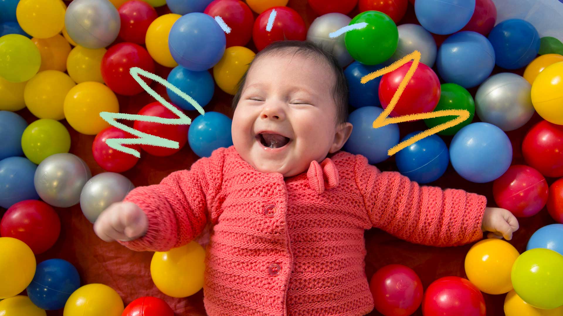 Imagem de um bebê sorrindo em cima de várias bolinhas de plástico