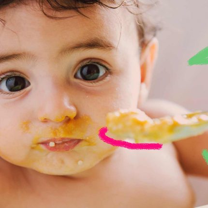 Imagem de um bebê comendo sua papinha com a boca suja. Seus olhos estão concentrados.