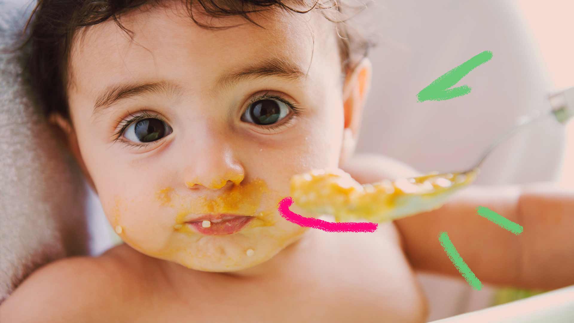 Imagem de um bebê comendo sua papinha com a boca suja. Seus olhos estão concentrados.