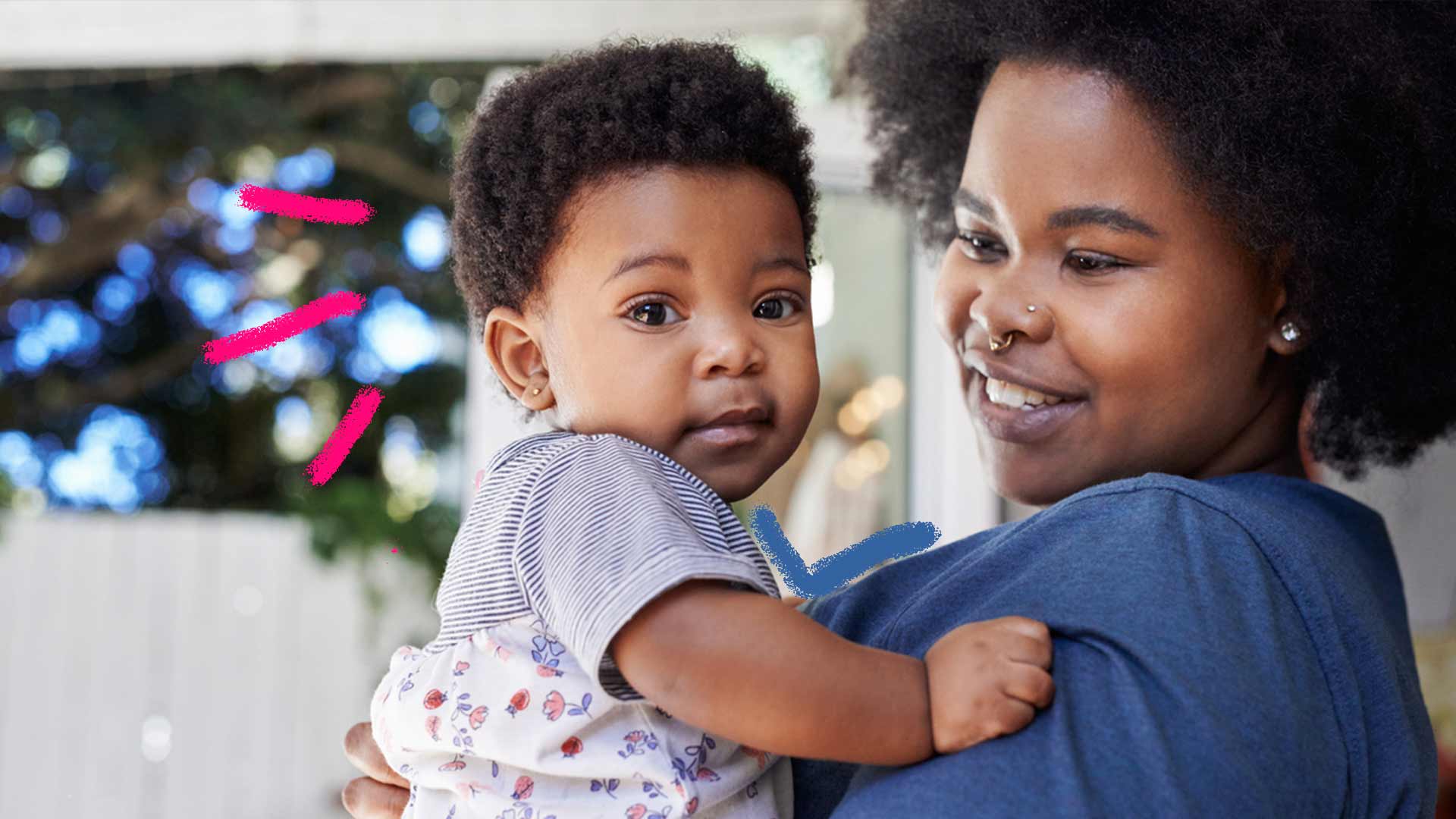 Imagem de uma mãe negra segurando seu bebê no colo. A mãe esta sorrindo