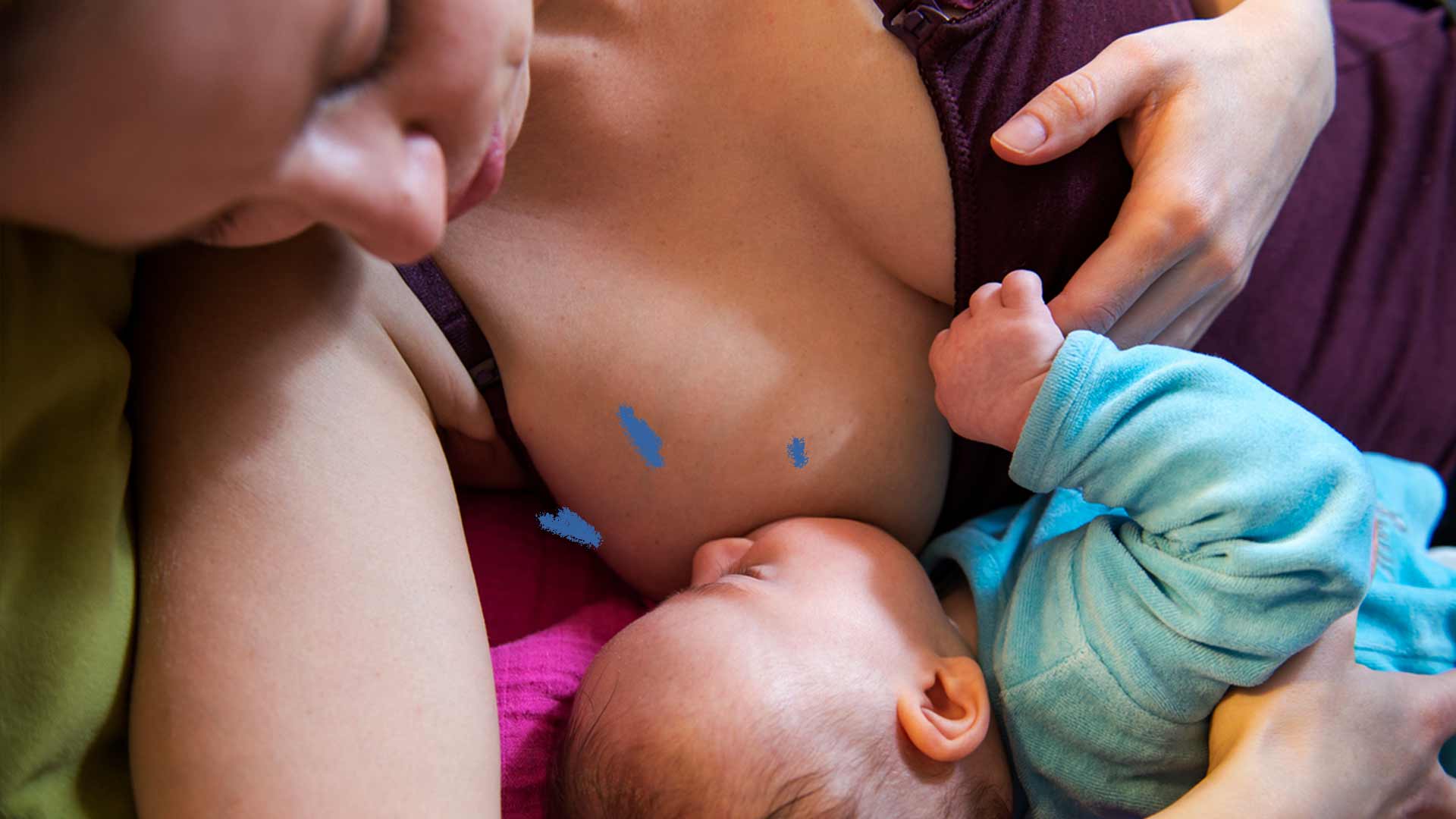 Imagem de uma mãe com o peito para fora da blusa amamentando seu filho