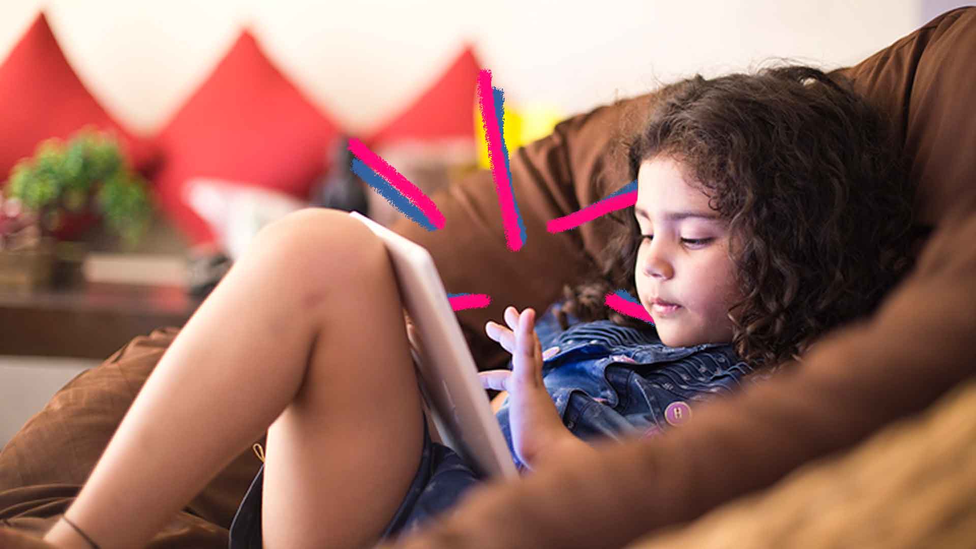 Imagem de uma menina deitada mexendo em um tablet que está apoiado na sua perna
