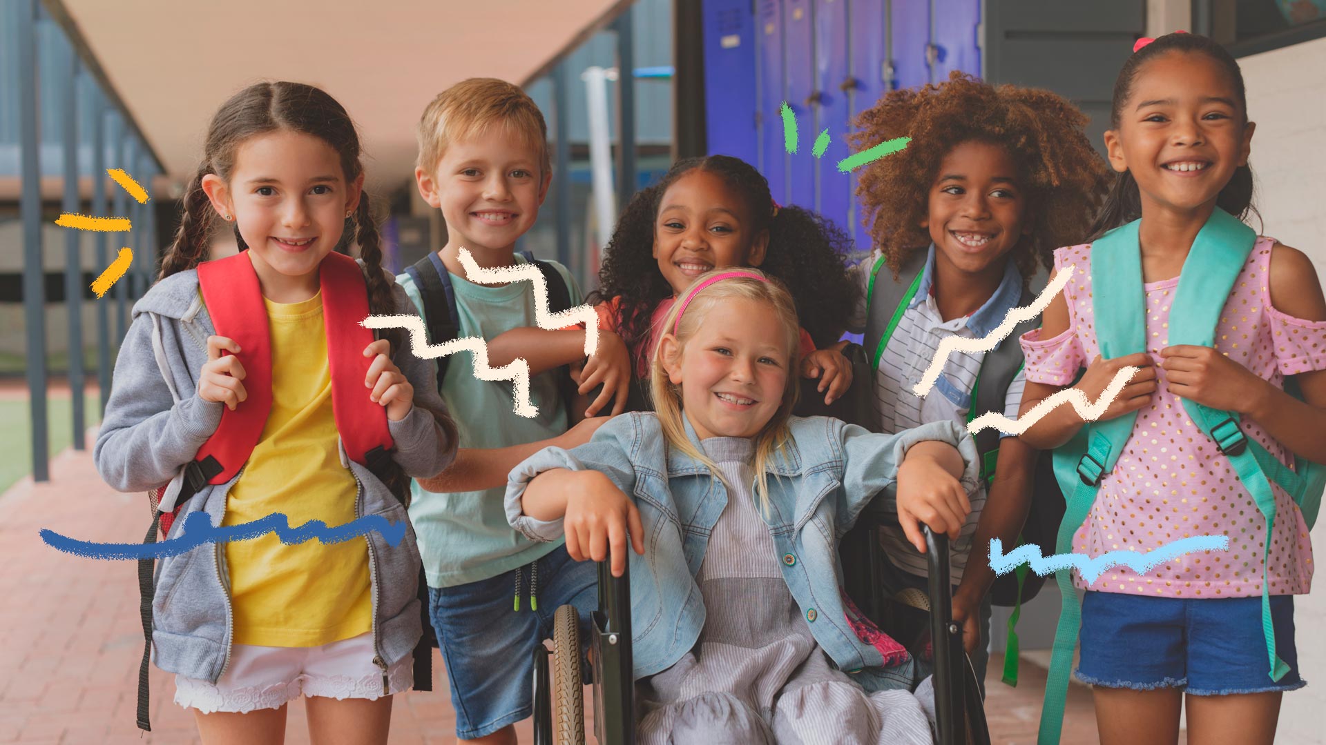 Foto de várias crianças em uma escola, posando e sorrindo para a foto. Uma delas, ao centro, é cadeirante.