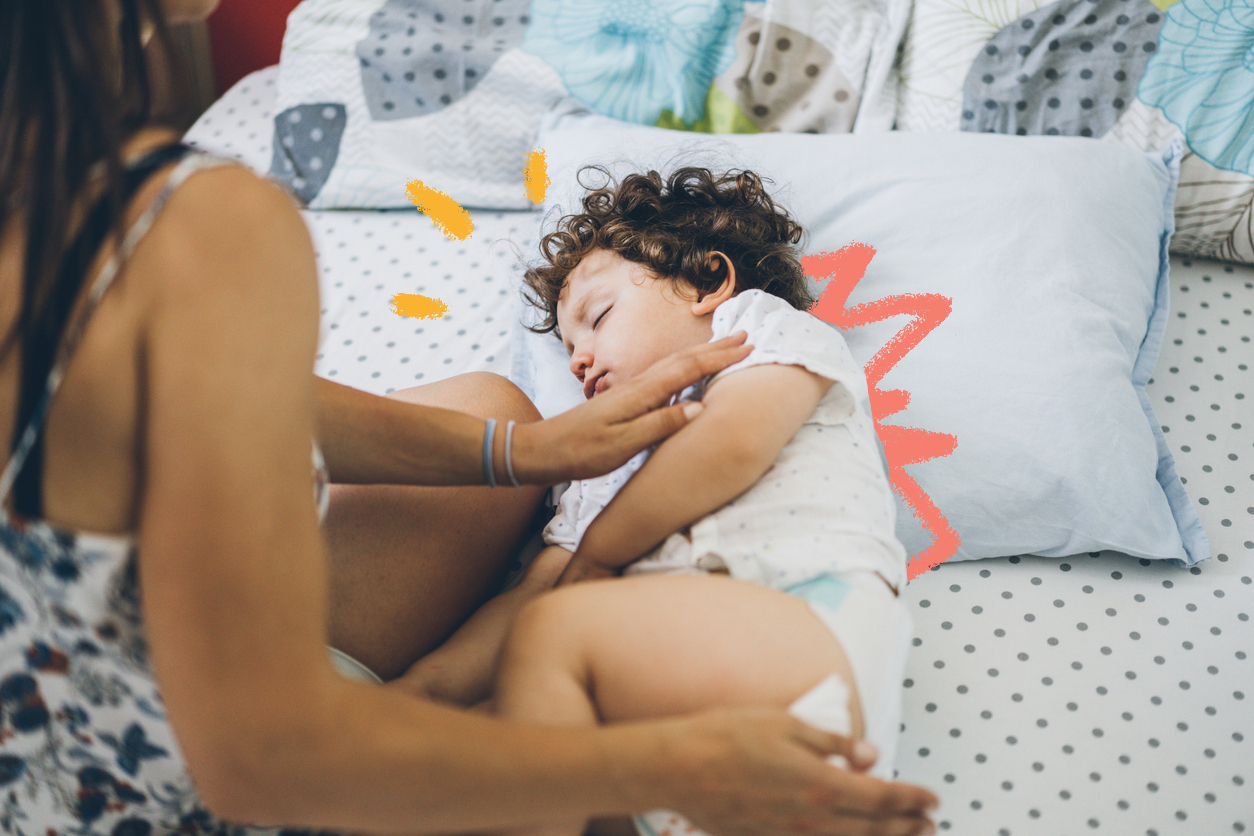 Imagem de uma criança deitada em uma cama. Sua mãe faz carinho enquanto dorme.