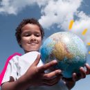 Imagem de um menino negro segurando um globo do mapa mundi