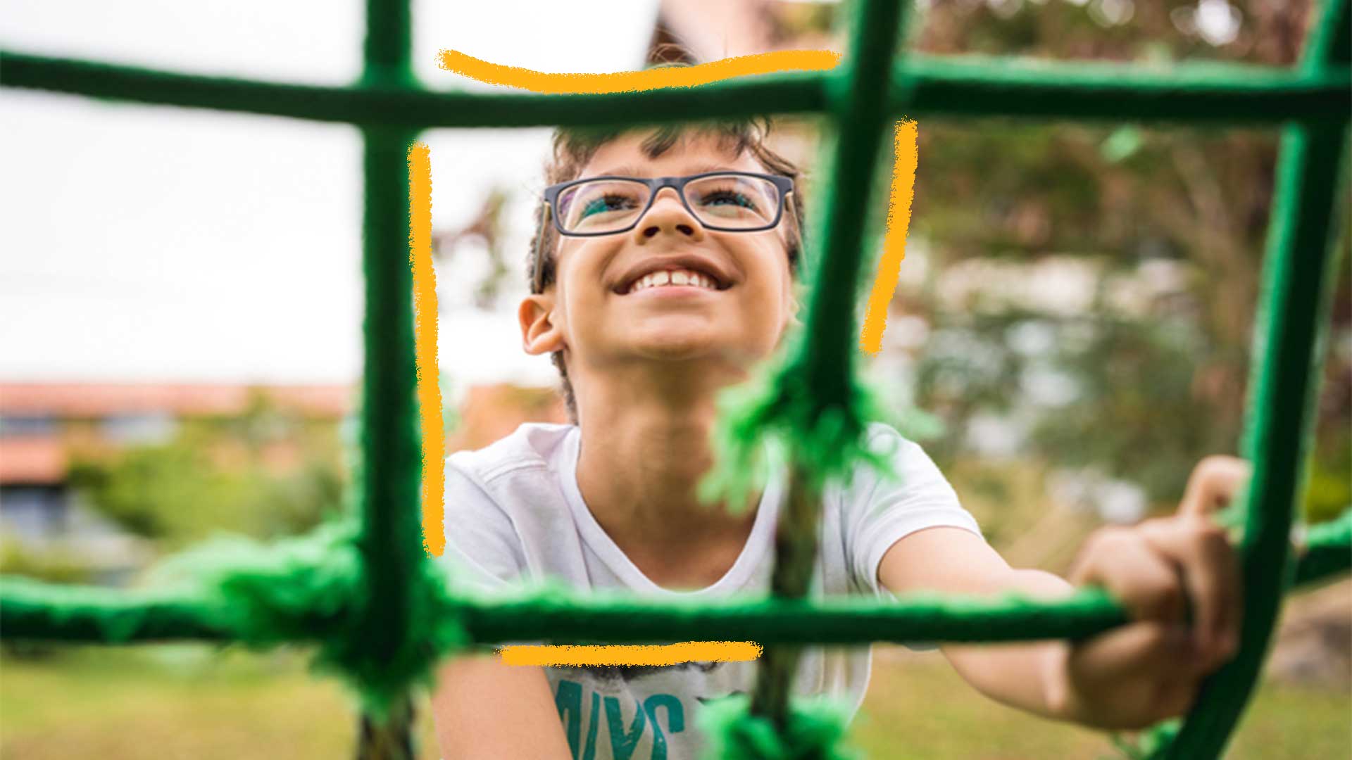 Foto de um menino com óculos sorrindo e subindo em uma corda na cor verde