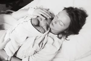 Foto em preto e branco de uma mulher que acaba de dar à luz seu bebê