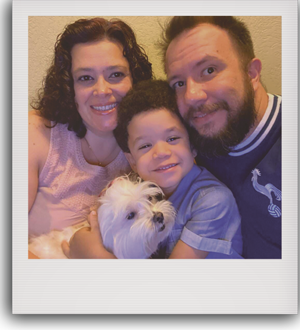 Foto de uma mãe, seu pai, e um filho com um cachorrinho em seu colo