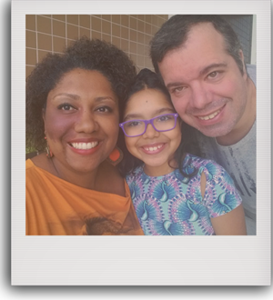 Foto de uma mulher negra, sua filha e seu esposo sorrindo