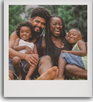 Foto de uma família negra sorrindo, os pais com duas crianças