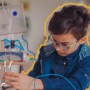 Imagem de um menino exemplificando brincadeiras sustentáveis com plástico, menino aparentando 12 anos está usando óculos e monta um robô com materiais reutilizáveis