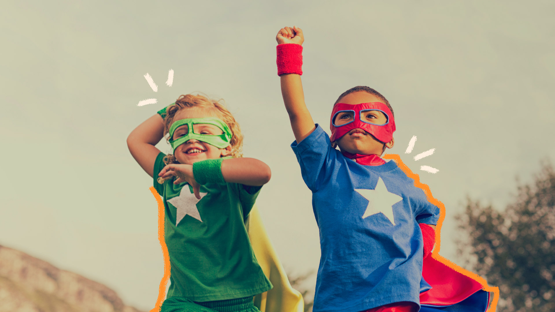 Imagem de dois meninos, um branco e um negro, estão vestidos com capas e máscaras de super-heróis