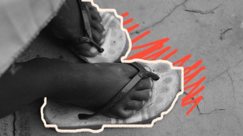 Imagem dos pés de uma criança negra usando uma sandália, expostos na rua. A imagem seria uma elucidação à exploração sexual infantil.