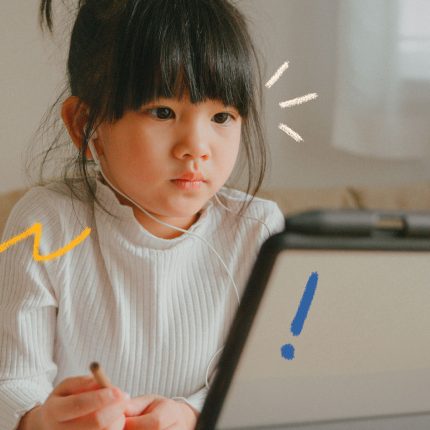 Cidadania digital: uma menina oriental está olhando para a tela de um computador enquanto segura também uma caneta prestes a colocar suas ideias em ação