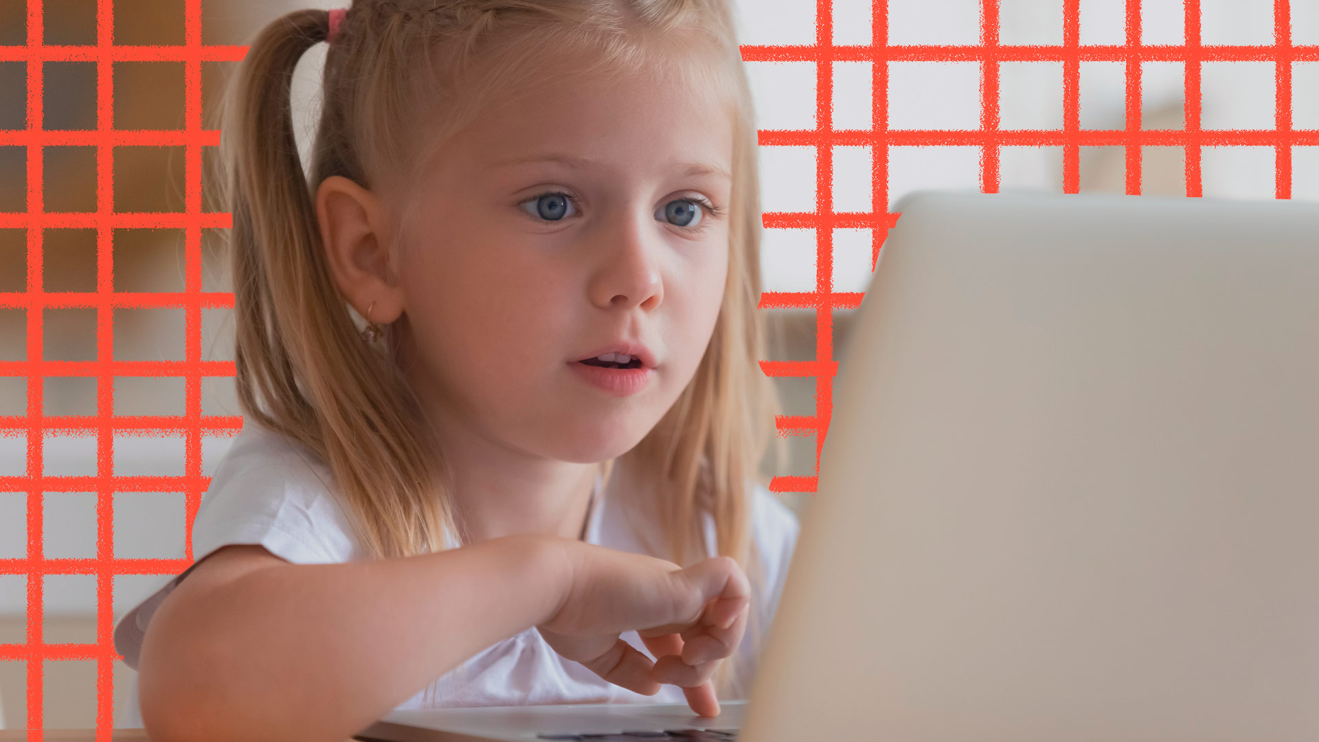 Foto de uma menina loira com o cabelo preso em maria-chiquinha. Ela olha atentamente para a tela de um notebook e passa o dedo pelo mouse