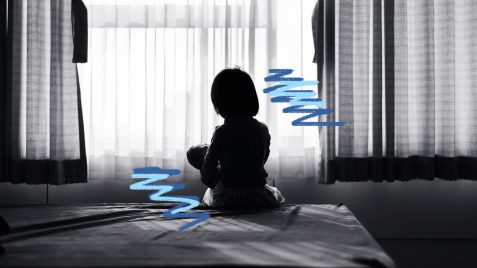 violência contra crianças: uma foto em preto e branco de uma menina sentada em cima de uma cama, de costas, olhando para uma janela