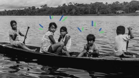 Demarcação de terras indígenas: oto em preto e branco de três crianças indígenas (2 meninas e 1 menino) em uma canoa, dentro de um rio, olhando para a câmera. Vê-se a floresta ao fundo.