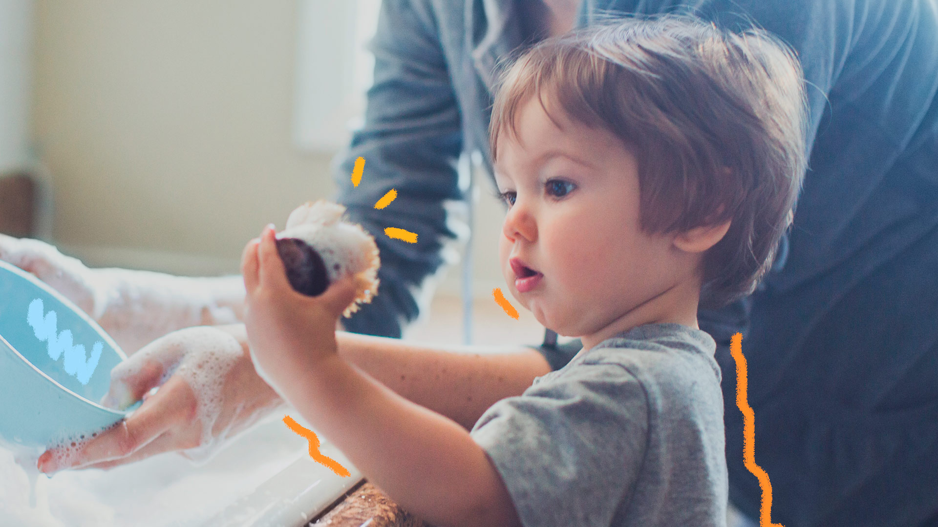 Imagem de um menino branco, de cabelos castanhos, aparentando dois anos está segurando uma esponja de lavar louças em matéria que discute masculinidades.