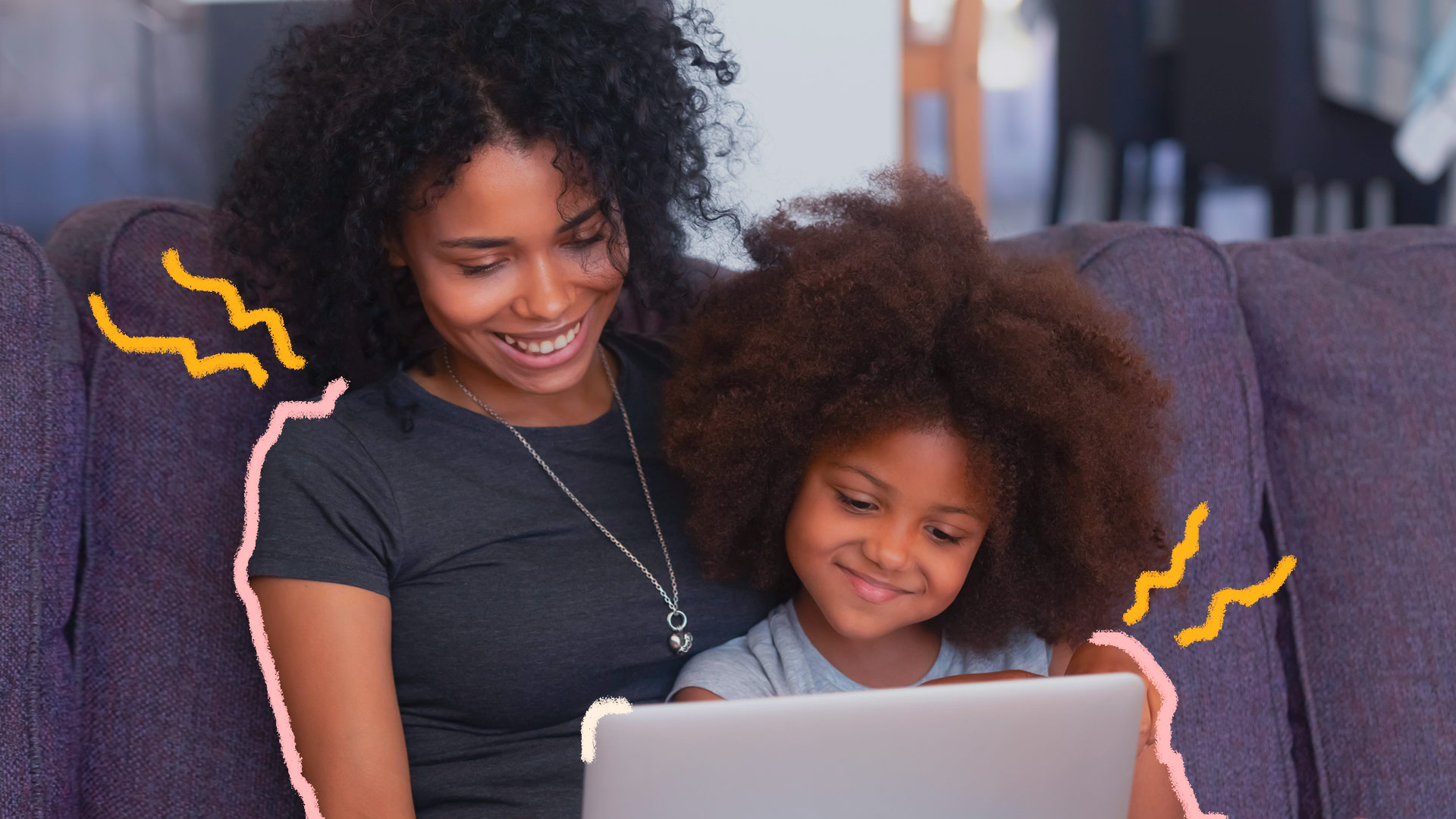 Mãe e filha, ambas negras, estão sorrindo enquanto assistem algo na tela do computador