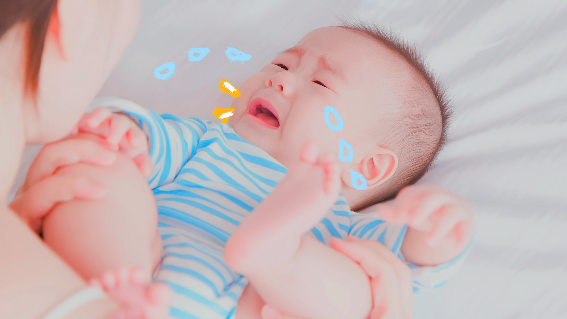 Imagem de um bebê vestido com uma roupinha azul listrada com branco está chorando