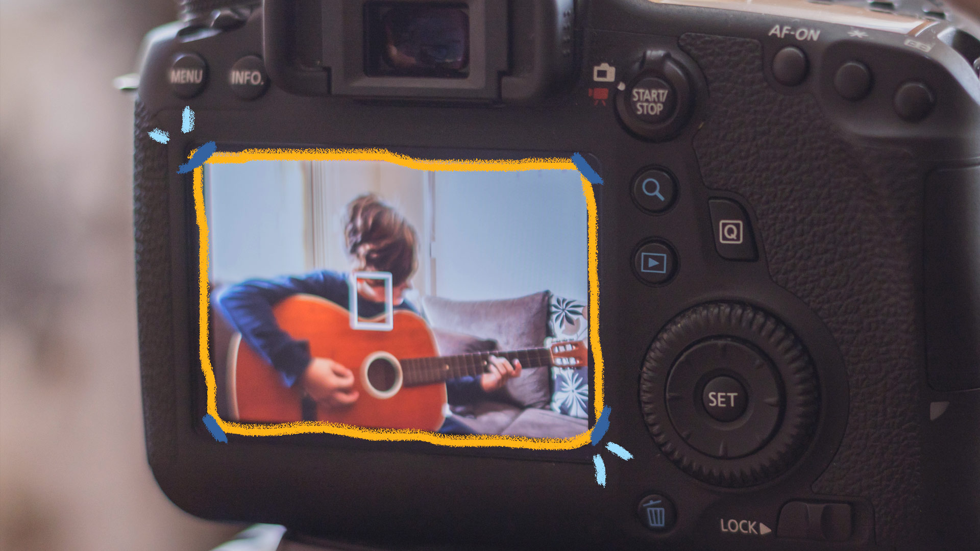 Através da lente de uma câmera digital, acompanhamos a gravação de um vídeo em que um menino toca um violão.
