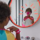 Representatividade negra: um menino vestido com fantasia de super-herói se olha pelo espelho do banheiro