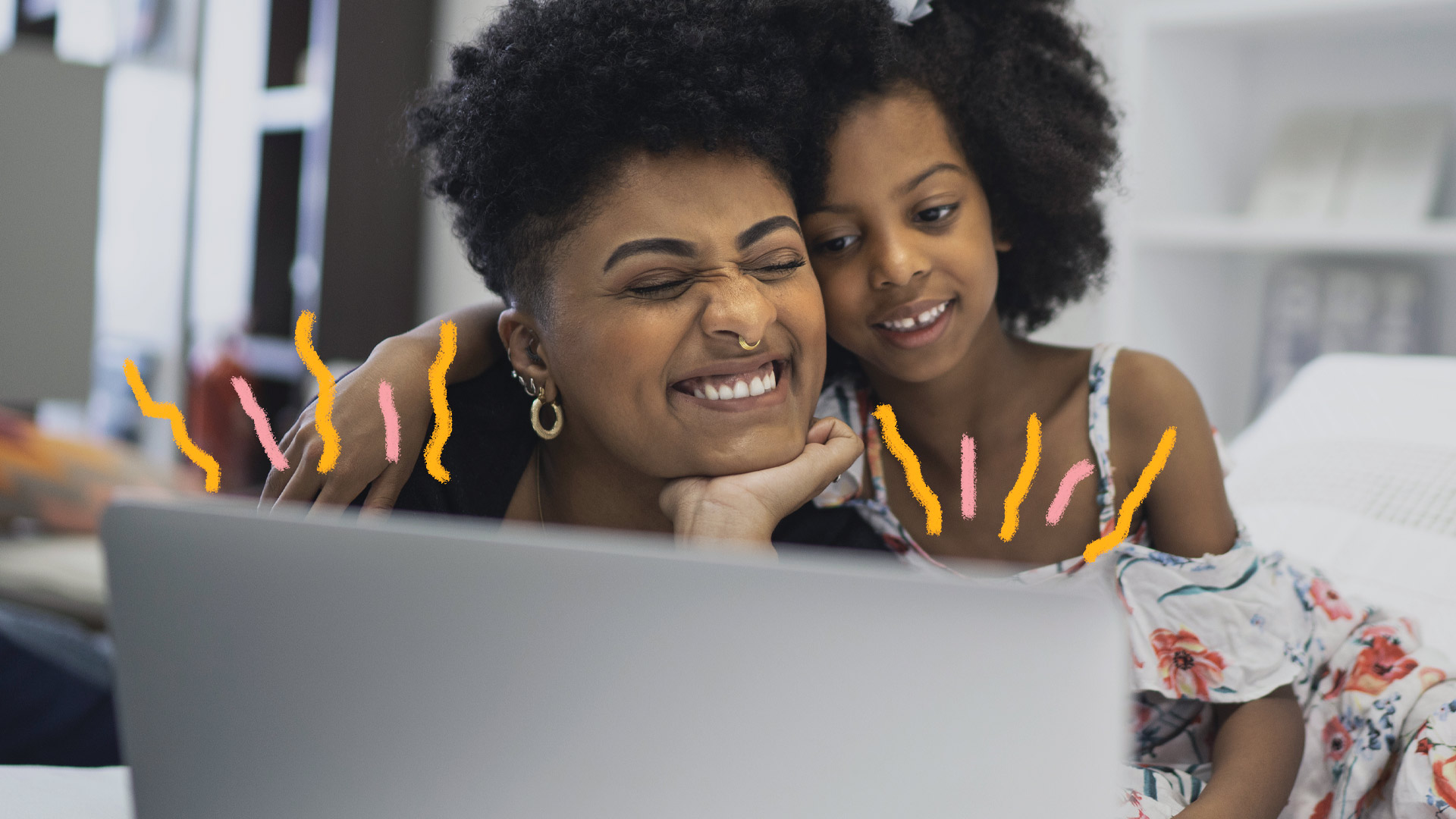 Imagem de uma mulher e uma menina negra se abraçando e sorrindo em frente a uma tela de computador