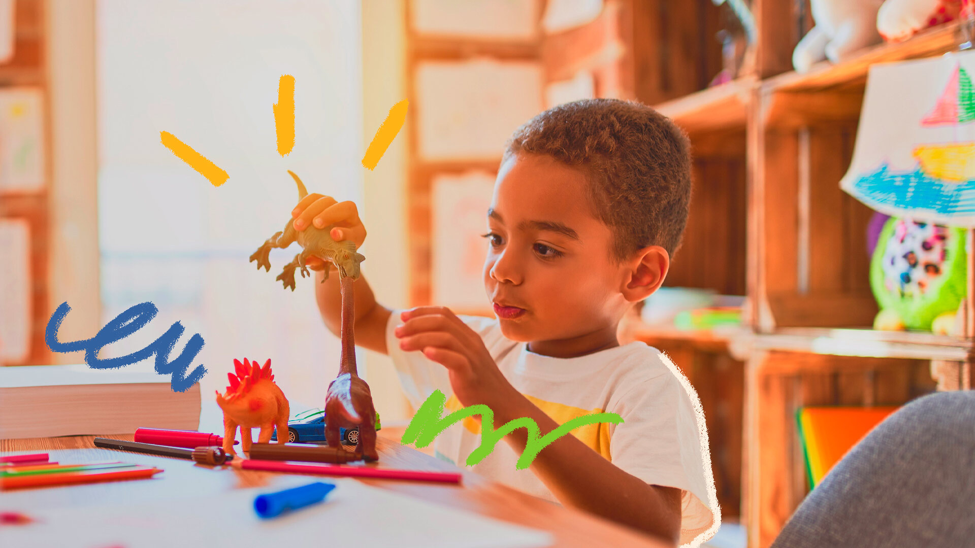 Foto de um menino brincando com seus dinossauros de plástico em cima de uma mesa, onde há também lápis de cor e canetinhas