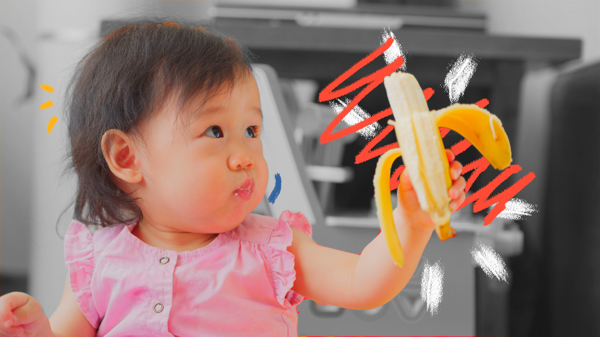 Suplemento alimentar infantil: foto de uma bebê asiática, que veste rosa está com uma banana descascada na mão.