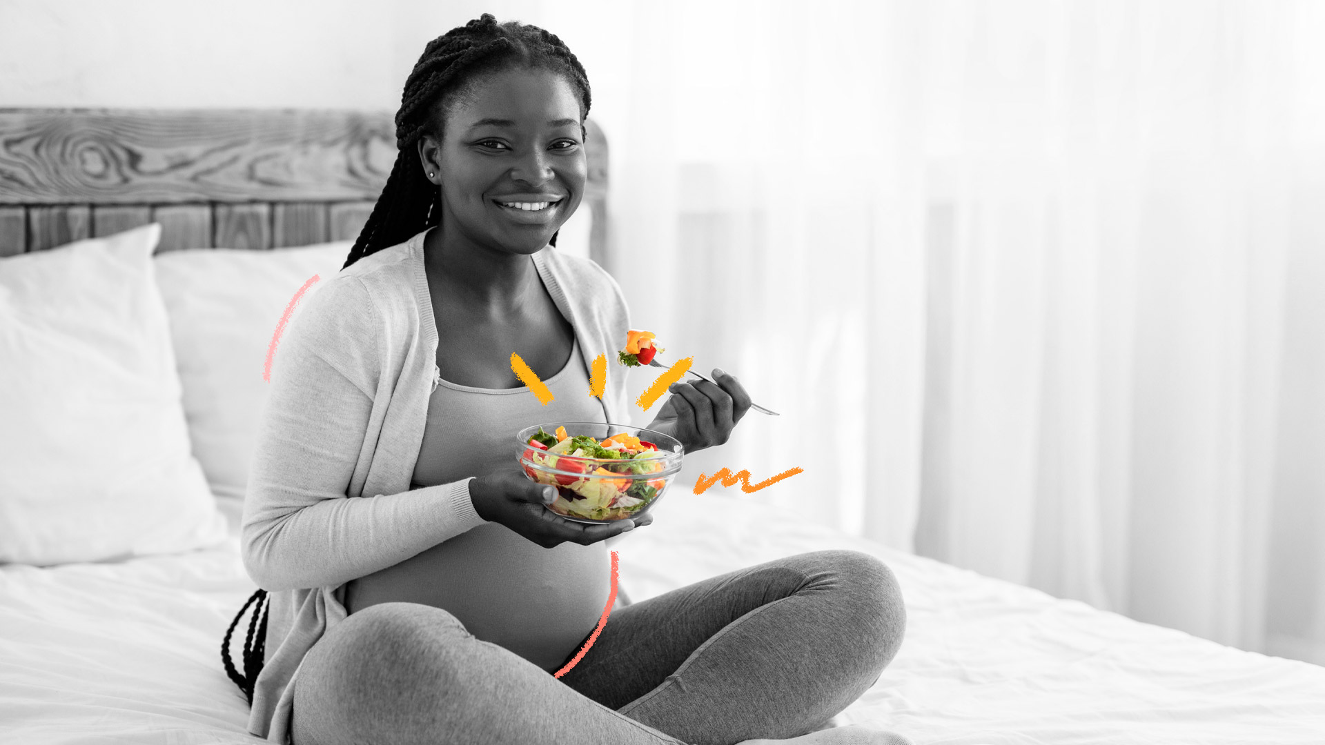 Alimentação na gravidez: foto em preto e branco de uma mulher grávida segurando um bowl com legumes (estes, coloridos) e sorrindo