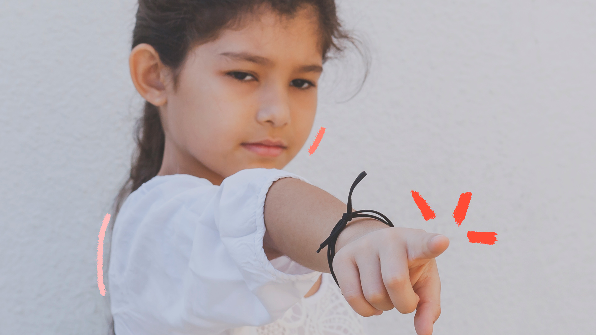 Foto de uma menina apontando o dedo. Ela veste branco, está com o cabelo preso e tem uma pulseira no braço. Texto sobre cancelamento e infância