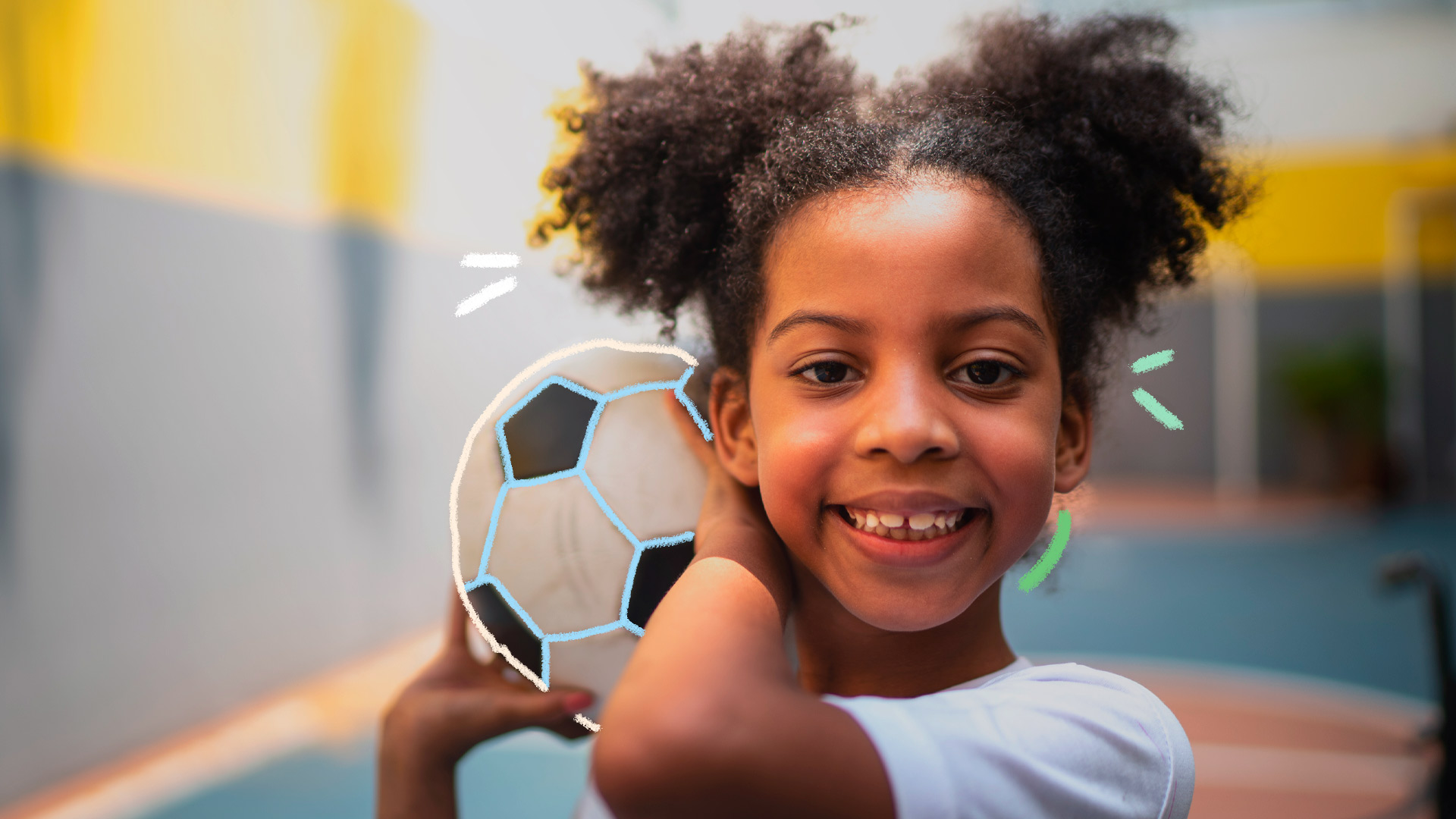Foto de uma menina segurando uma bola de futebol ao lado do rosto