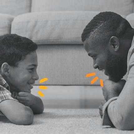 Jogo de palavras: foto em preto e branco de pai e filho deitados de bruços na sala de estar, olhando um para o outro e falando