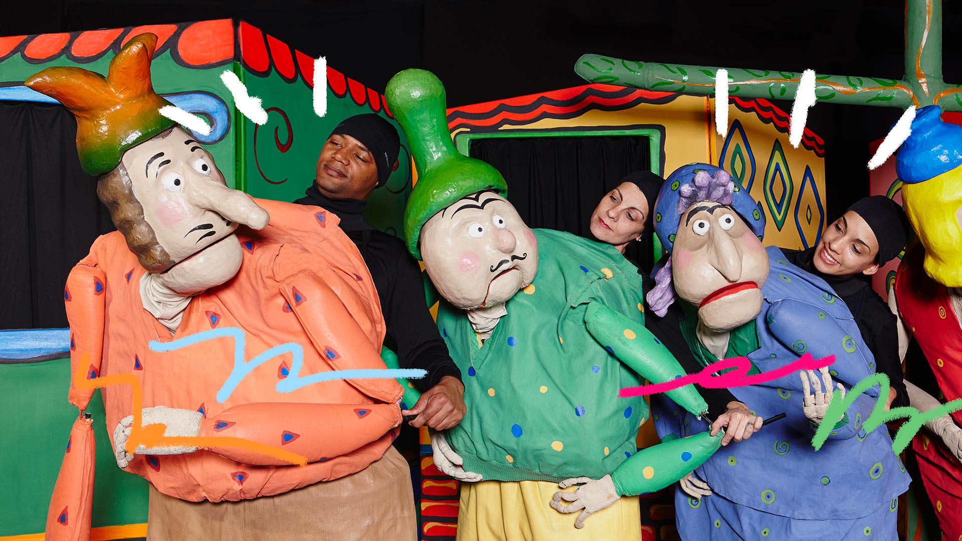 Ator e atrizes do espetáculo Cocô de Passarinho aparecem sorridentes ao lado de bonecos coloridos com semblantes de dúvida