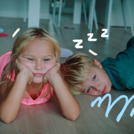 Um menino e uma menina ambos loirinhos, estão deitados no chão com cara de entediados.