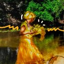 Crianças na umbanda: Uma menina vestindo vestindo longo e turbante amarelo, com oferendas amarelas, está em frente a um rio