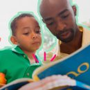 Livros por faixa etária: Foto de um homem e uma criança, ambos negros, lendo um livro