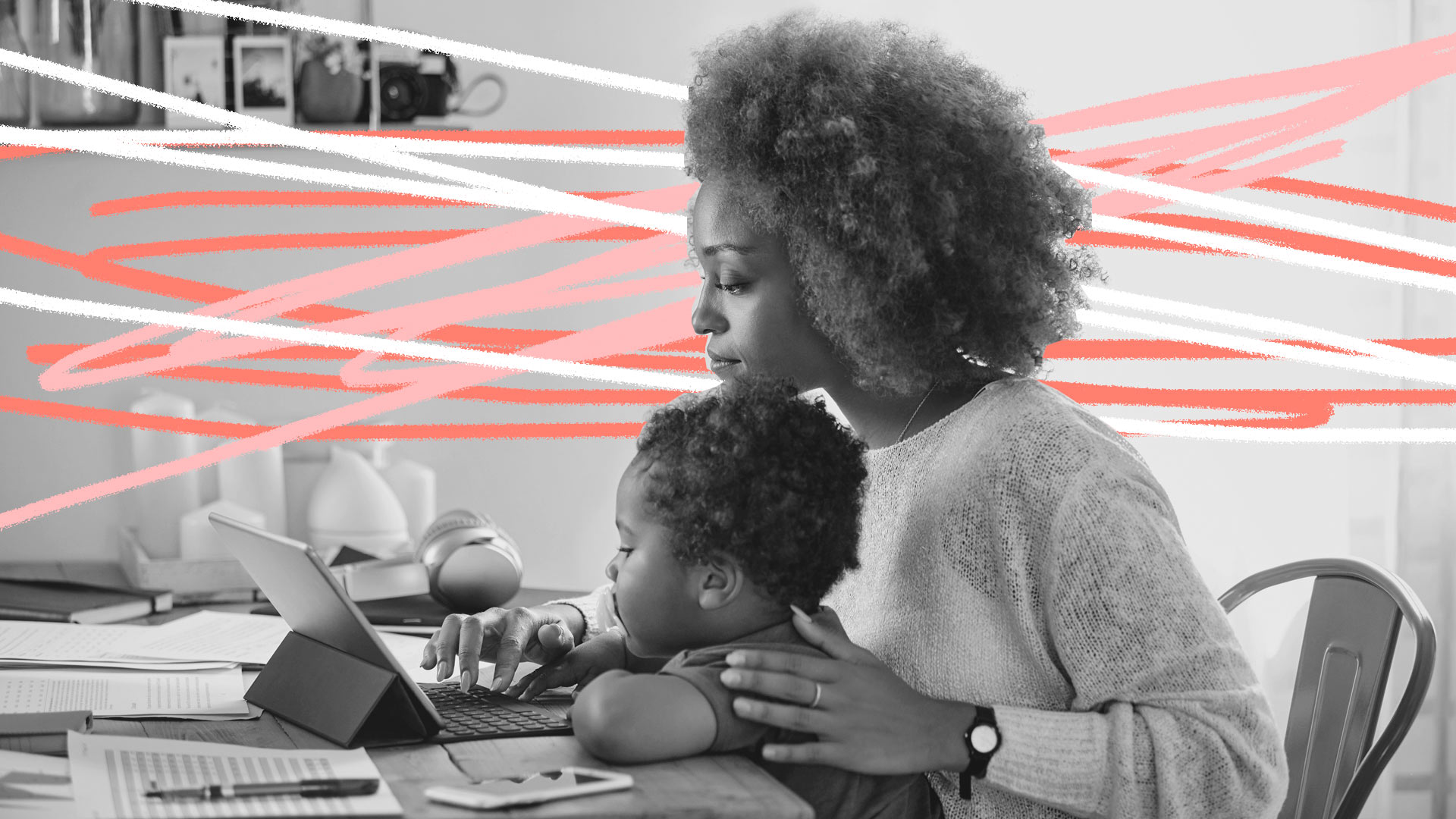 Mães solo e carreira: foto em preto e branco de uma mãe e filho, ambos negros. Ela está trabalhando em frente ao computador enquanto tem o bebê no colo.