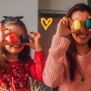 duas meninas estão sorrindo e segurando ovos de Páscoa coloridos nos olhos