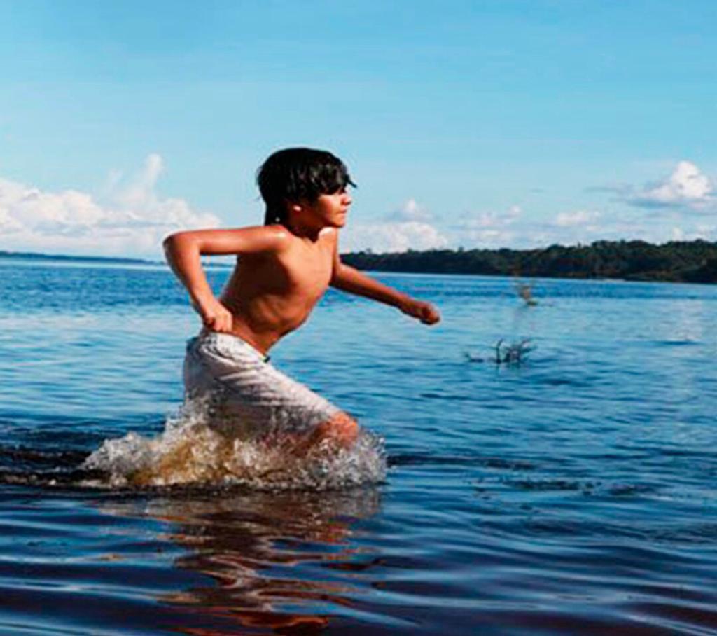 Crianças da Amazônia: Foto de um menino vestindo bermuda e correndo em um rio