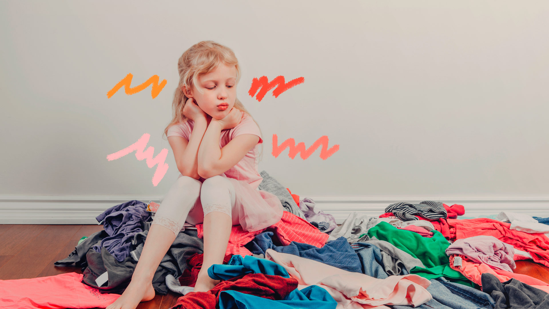 Depressão e consumismo: Uma menina está sentada em cima de uma pilha de roupas e olha para elas com uma expressão chateada