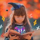 Medo na literatura infantil: Foto de uma menina com chapéu de bruxa com um livro aberto nas mãos