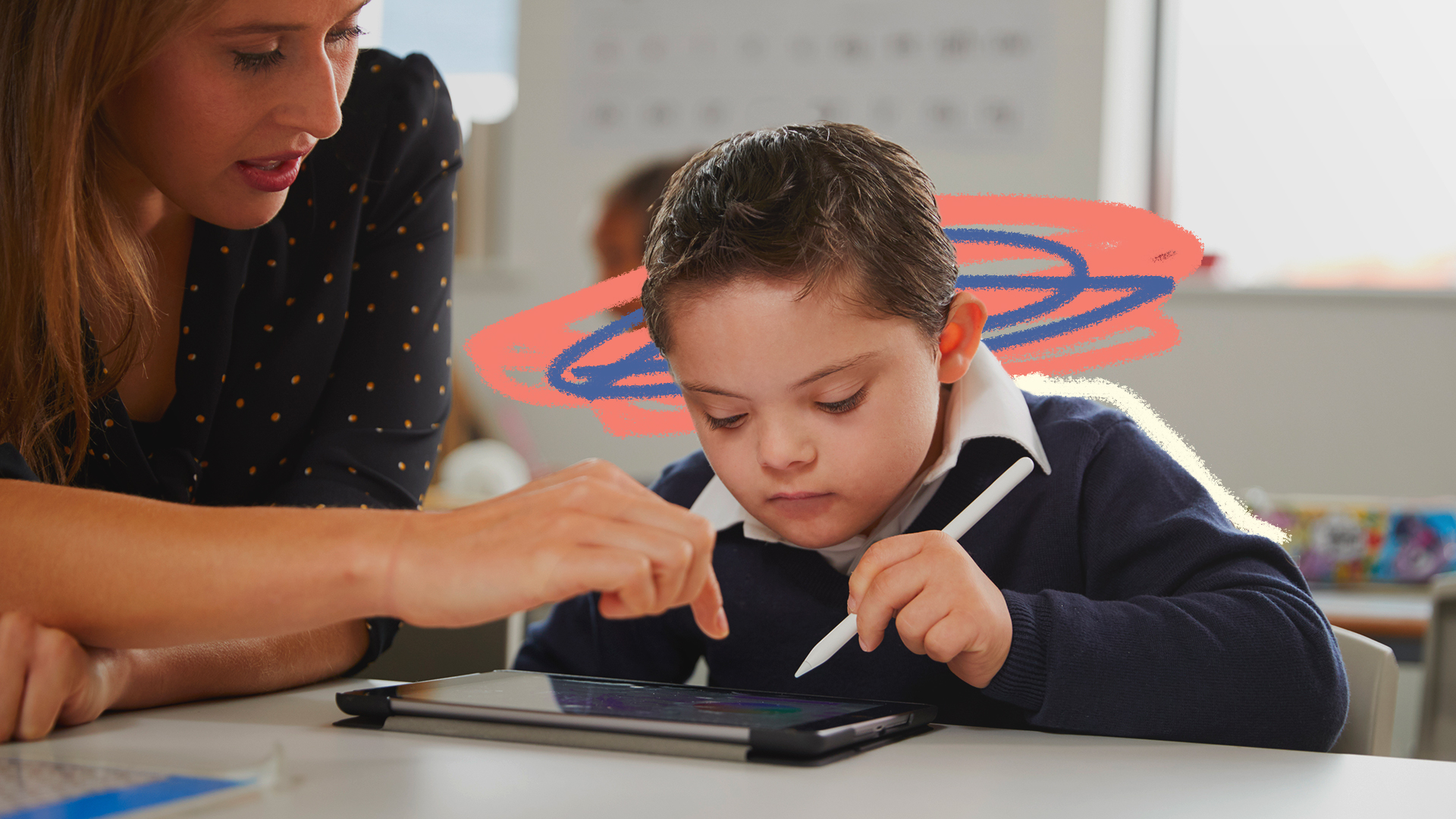 Na foto, um menino de pele clara utiliza um tablet com auxílio de uma caneta, com orientação de sua professora